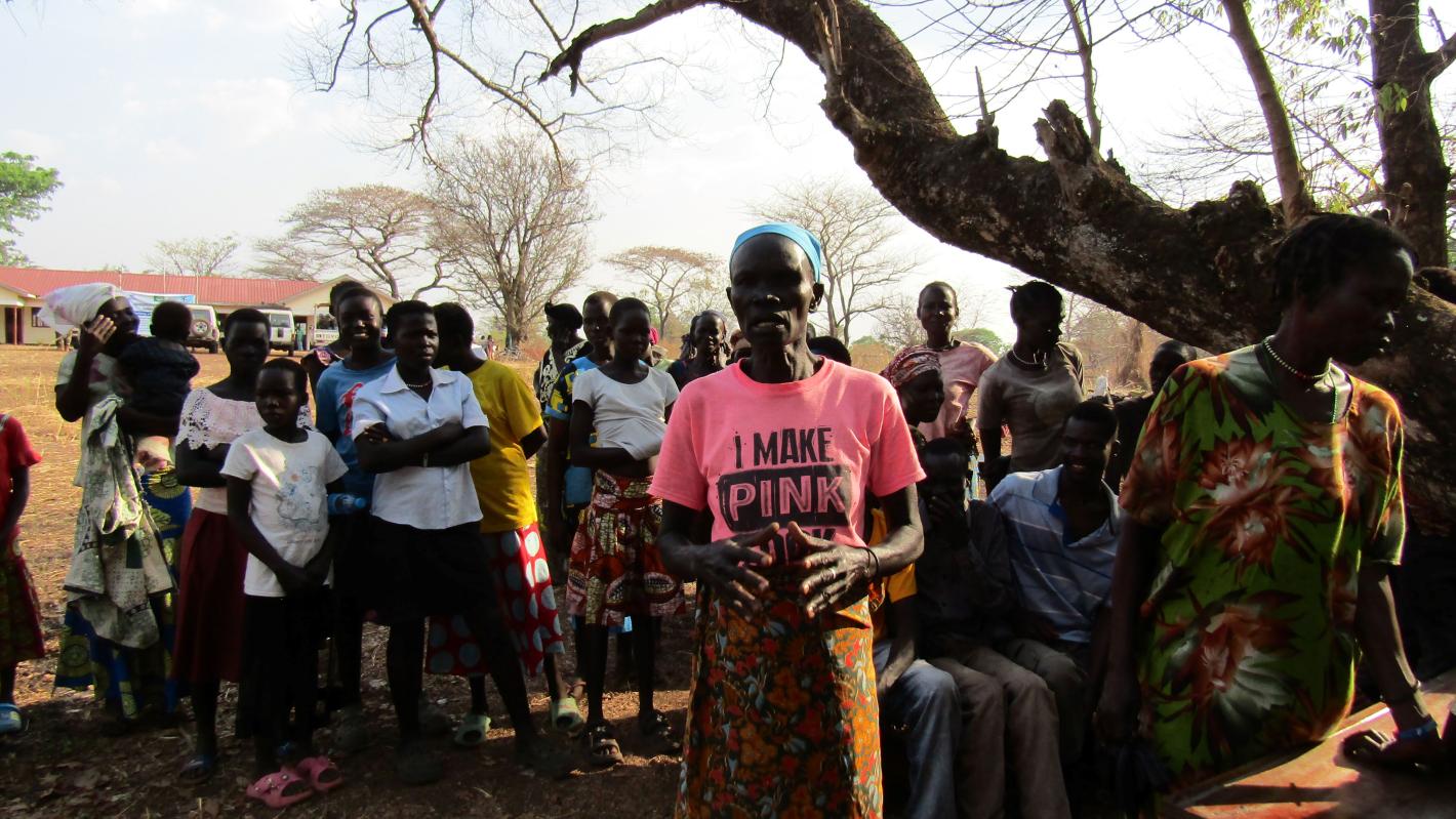 A group of women standing underneath a tree. The woman in the centre is wearing a pink t-shirt that says "I make pink"