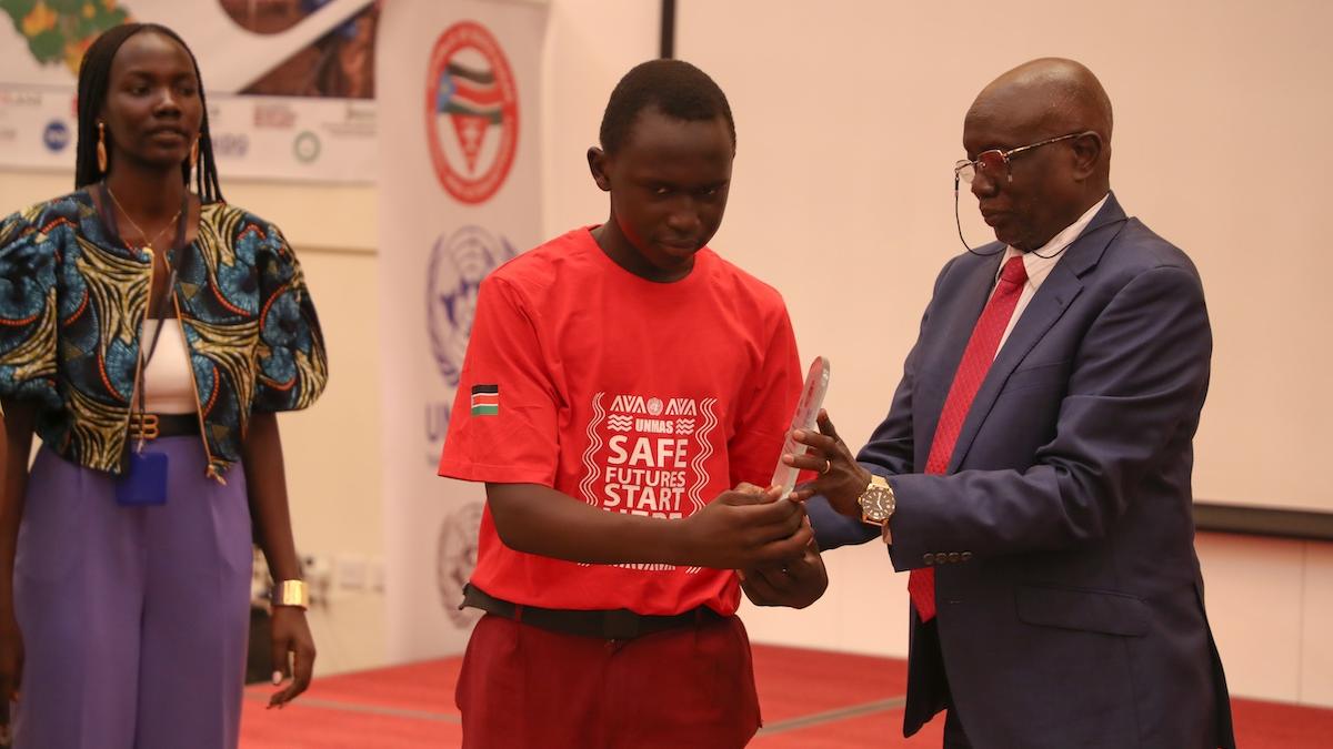 A man in a suit handing an item to a boy wearing a red t-shirt