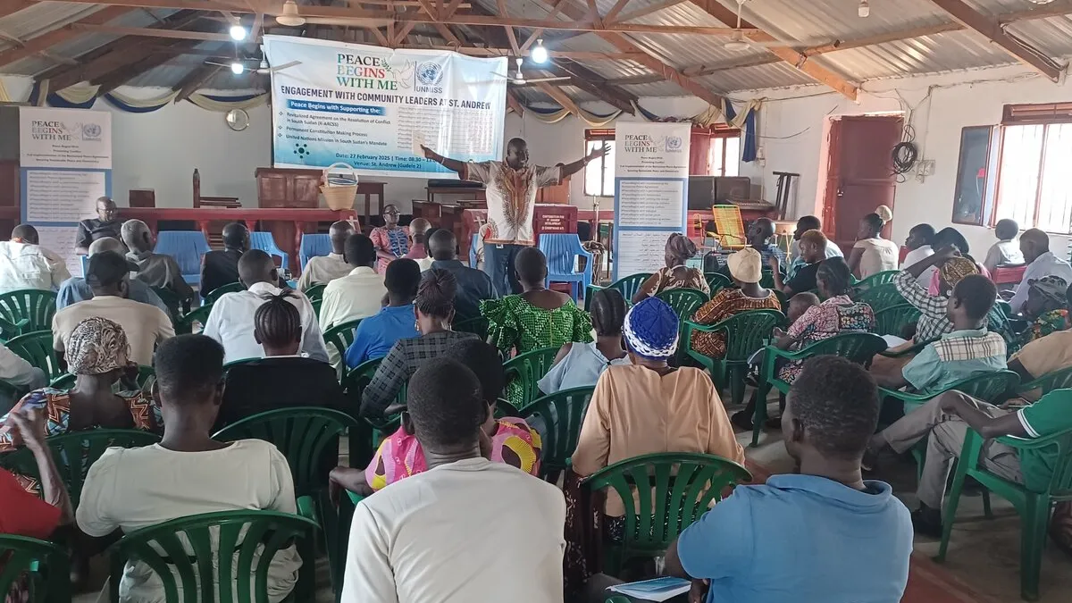 Freedom of expression and inclusion in preparations for elections were the hot topics at an UNMISS-hosted dialogue for 80 members of the Gudele community in Juba. A group of people seated in green plastic chairs seated facing a stage where a man is presenting with their arms outstretched.