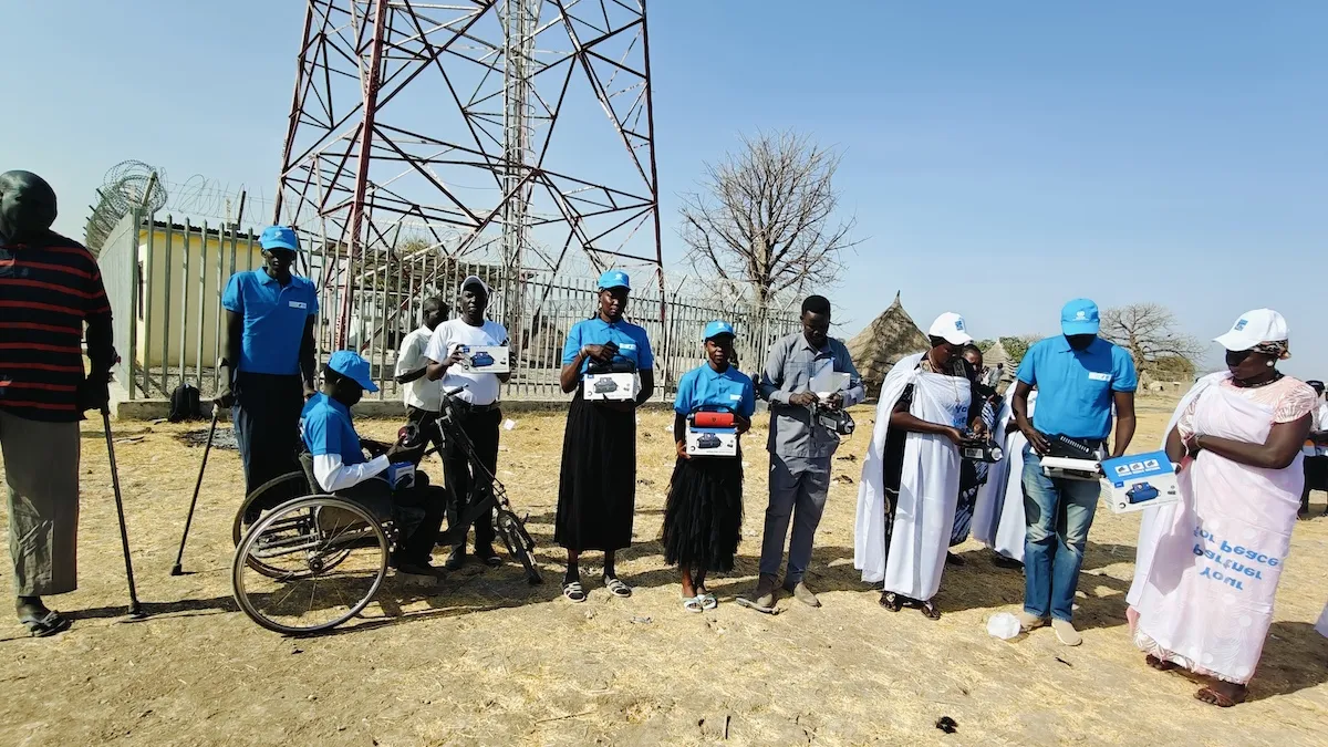 A new Radio Miraya transmitter was launched in Mayom during an event that also celebrated International Women's Day. Photos: Taban Geofrey Koma Alfred/UNMISS A group of people standing in front of a radio transmitting tower.