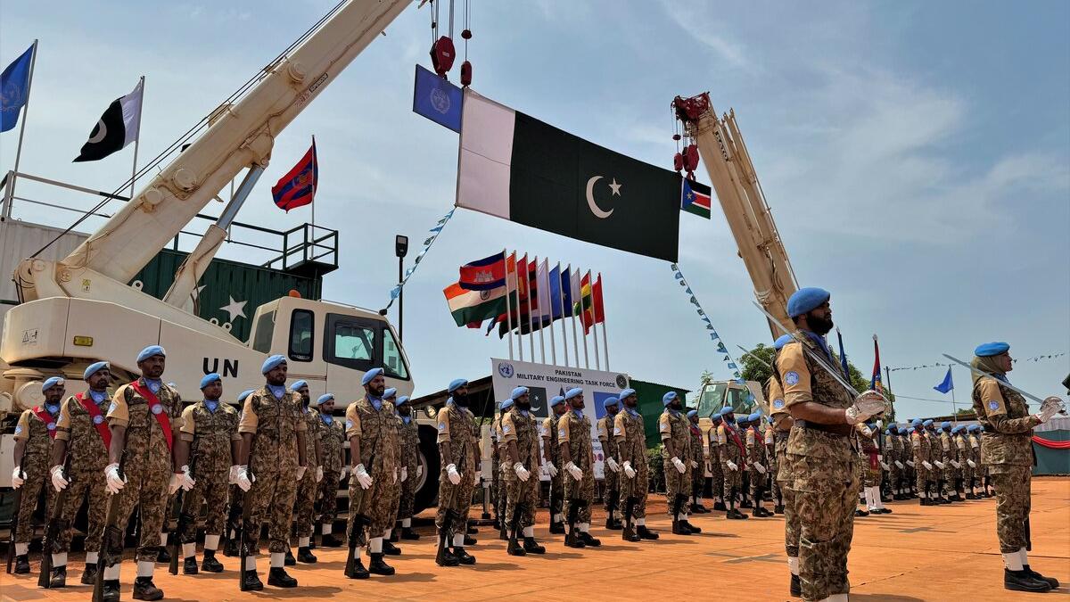 Pakistani peacekeepers standing in formation under the Pakistani flag.