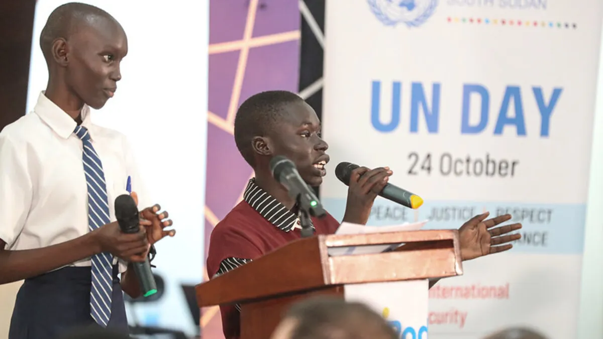 On the 80th anniversary of the United Nations, a vibrant event was held to mark the Organization’s contribution to peace and development in South Sudan, including a storytelling photo exhibition of the UN contributions in the country. Two individuals speaking at a podium with microphones during a UN Day event, with a banner showing ‘UN Day 24 October’ in the background.