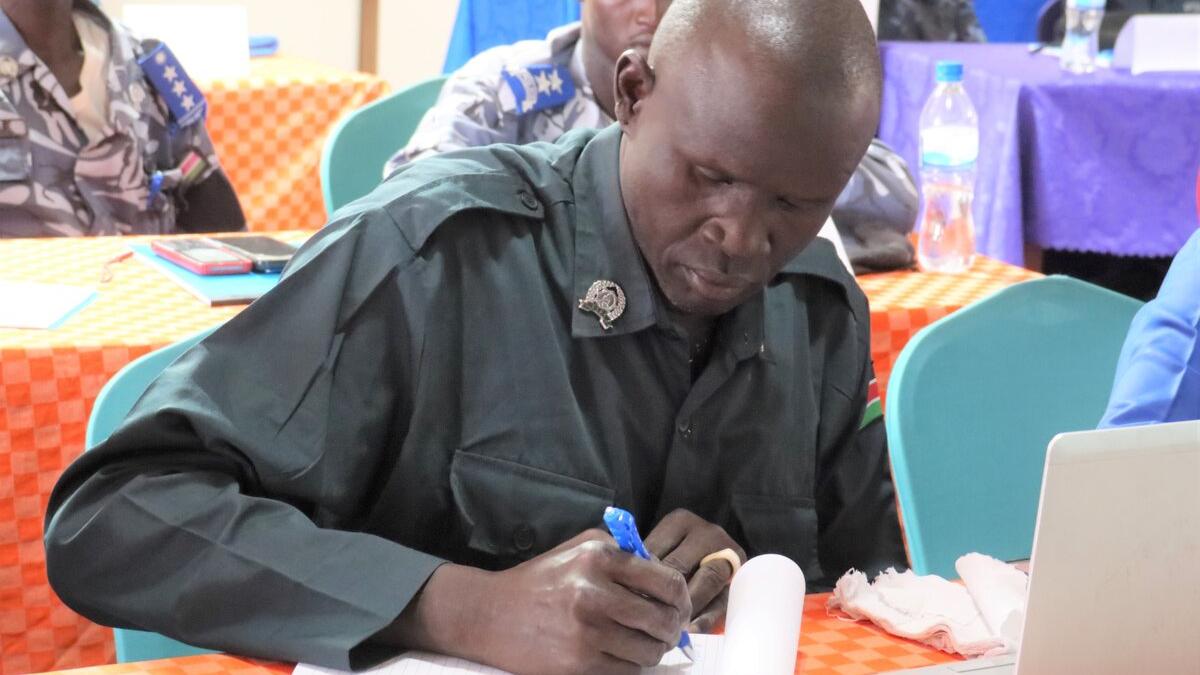 Police officer looking down, writing with a blue pen