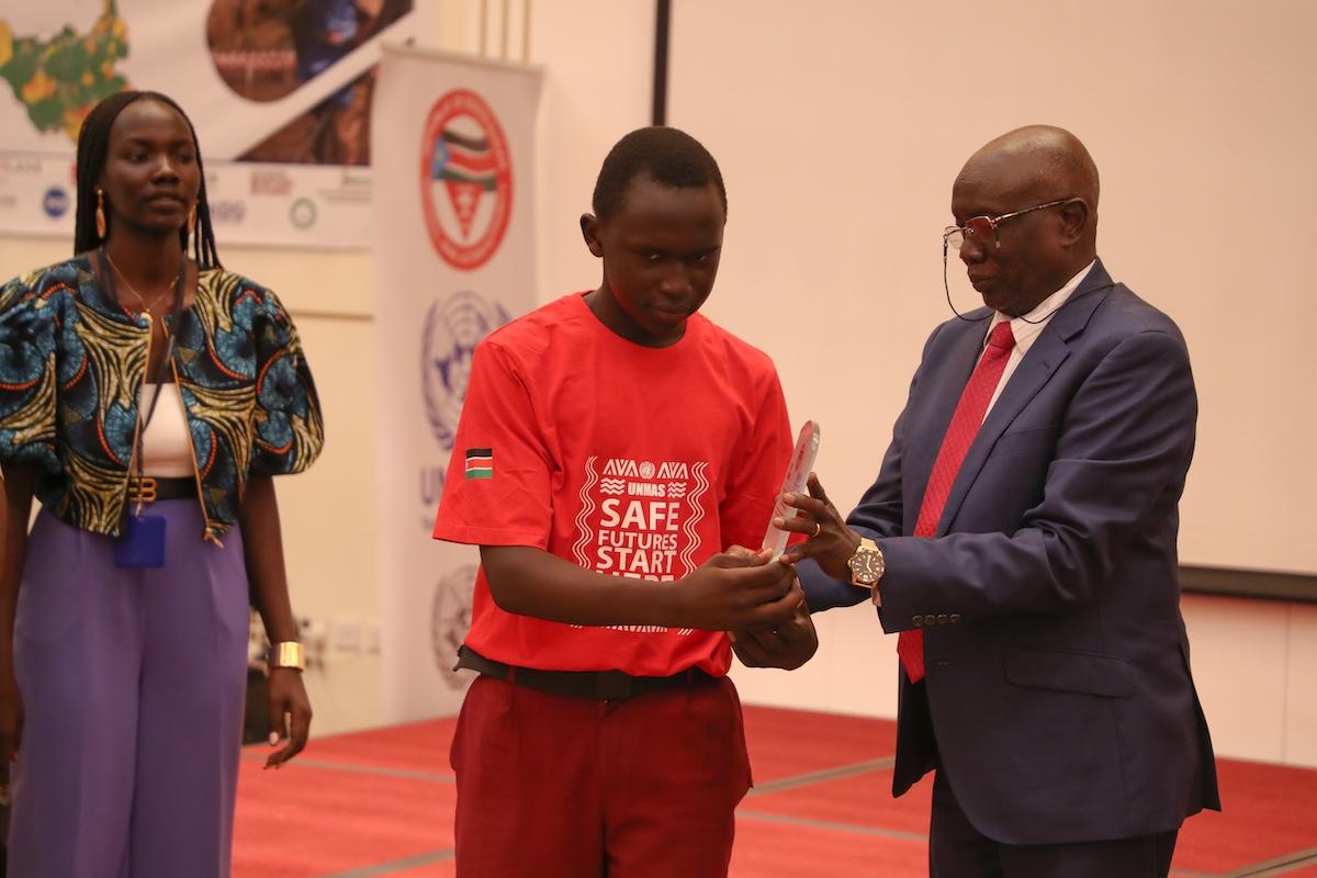 A man in a suit handing an item to a boy wearing a red t-shirt