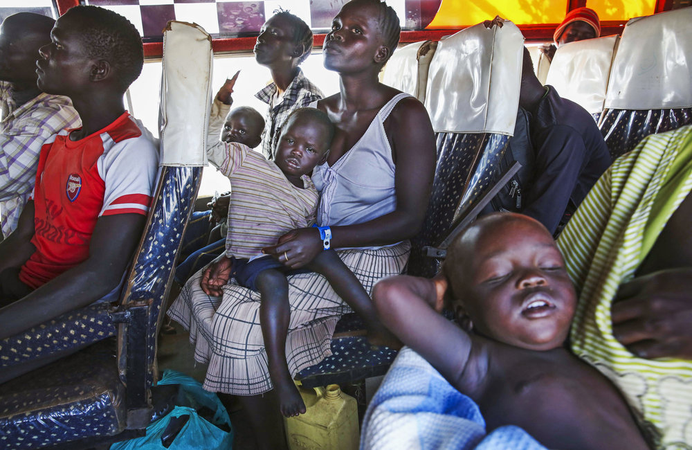 South Sudanese refugees wait for their intake cards while arriving on a transit bus to the reception center at the Imvepi Refugee camp on Friday, 23 June, 2017 in Northern Uganda. 